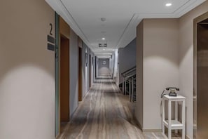 Een hotelgang met een marmeren vloer, een receptiebalie en een trap.