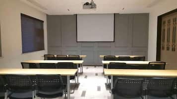 A conference room with a projector screen, tables, and chairs.