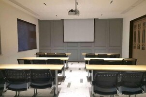 A conference room with a projector screen, tables, and chairs.