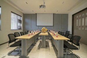 A conference room with a long table, chairs, a projector, and a screen. - Magnotel Hotel (Qufu Sankong Scenic Area Chunqiu West Road) (Qufu)