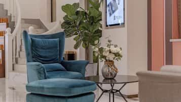 A modern living room with a blue armchair, a round coffee table, and a potted plant.