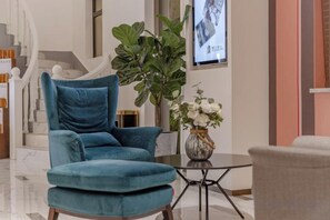 Un salon moderne avec un fauteuil bleu, une table basse ronde et une plante en pot.