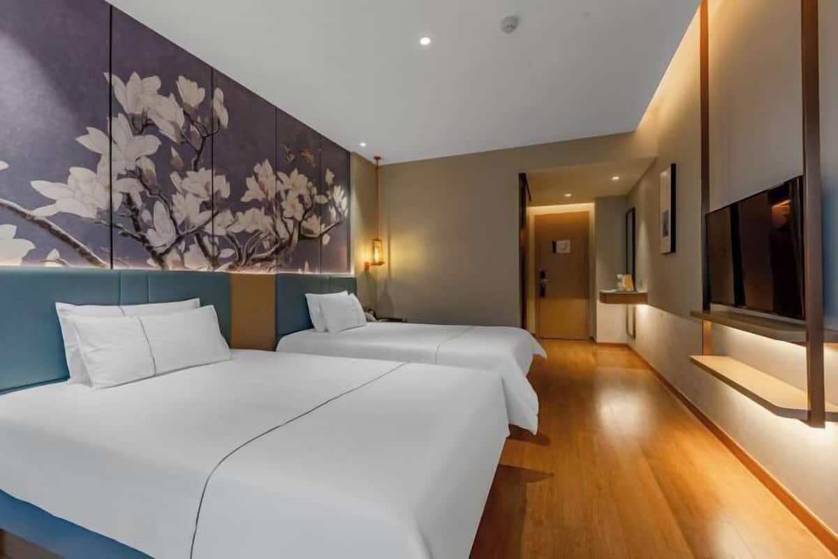 Une chambre d’hôtel avec deux lits, une grande œuvre d’art florale au mur, une télévision et un plancher en bois.