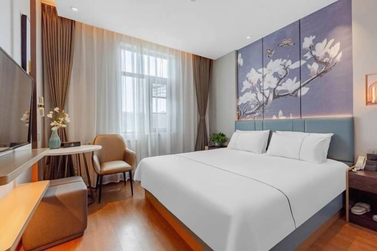Une chambre d’hôtel avec un lit, un bureau, une chaise, une télévision et un tableau au mur.