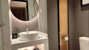 A modern bathroom with a round mirror, a white sink, and a toilet.