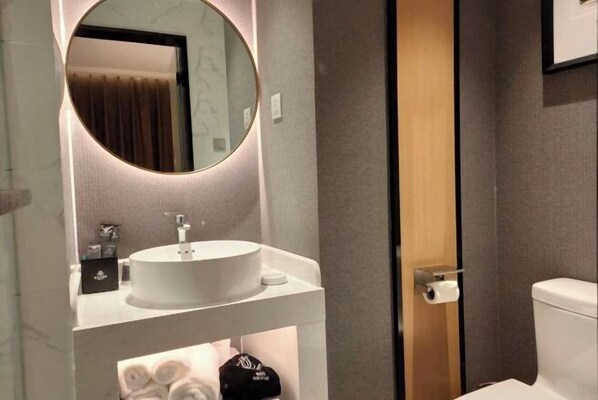 Une salle de bain moderne avec un miroir rond, un lavabo blanc et des toilettes.
