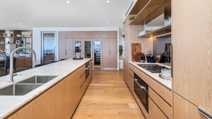 A modern kitchen with wooden cabinets, a central island with a sink, and a built-in oven.