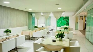 A modern hotel lobby with white furniture, green accents, and a glass partition wall. - Jinjiang Inn (Weihai Liugong Island Scenic Area Weigao Square Branch) (Weihai)