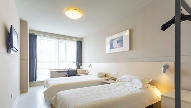 A hotel room with two beds, a desk, a chair, a TV, and a window with curtains. - Jinjiang Inn (Weihai Liugong Island Scenic Area Weigao Square Branch) (Weihai)