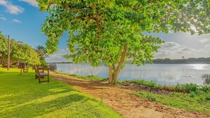 A park with a bench, a tree, and a lake. - GB105 Porto Smeralda Guarajuba a 150m da praia (Camaçari)