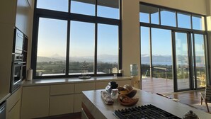 A kitchen with large windows, a gas stove, and a view of a mountainous landscape.