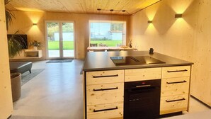 Una cocina moderna con armarios de madera, encimera negra y horno empotrado.