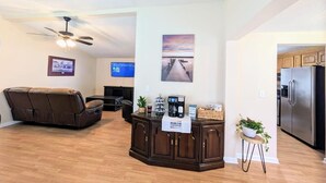 A modern living room with a brown leather sofa, a wooden entertainment center, a ceiling fan, and a kitchen area with a stainless steel refrigerator. - Heaths Cove on Lake Murray with 3 bed 3 baths. Beautiful lake views and dock (Prosperity)