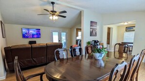 A dining area with a round wooden table and eight chairs, a ceiling fan, and a television on the wall. - Heaths Cove on Lake Murray with 3 bed 3 baths. Beautiful lake views and dock (Prosperity)
