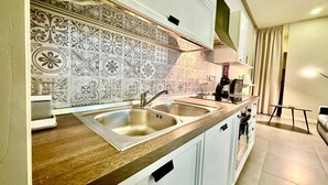 A modern kitchen with two sinks, white cabinets, patterned backsplash, and a wooden countertop. - Stylish 1 Bedr Apt next to The sea Front (Il-Gzira)