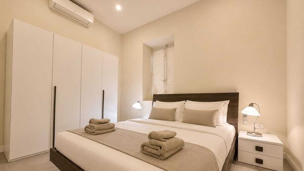Un dormitorio con cama, mesitas de noche, armario y equipo de aire acondicionado.