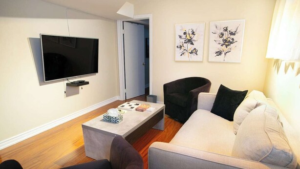 A modern living room with a flat-screen TV, a sofa, a chair, and a coffee table.