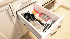 A kitchen drawer with various utensils including a grater, spatula, and ladle.