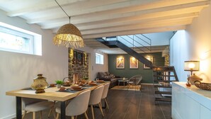 A modern dining area with a wooden table and chairs, a hanging light fixture, and a staircase leading to an upper level. - La Loc'Oyarn - Maison avec parking privé (Hennebont)