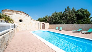 A swimming pool with a stone wall and a wooden deck.