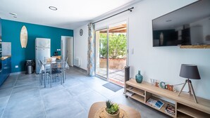 A modern kitchen with a blue wall, a surfboard decoration, and a dining area with a table and chairs.