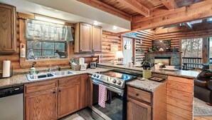 A log cabin kitchen with wooden cabinets, a stove, and a sink.