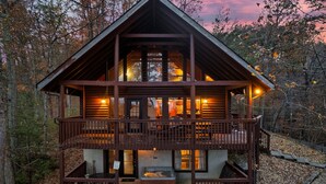 A two-story log cabin with a balcony, a hot tub, and a fireplace.