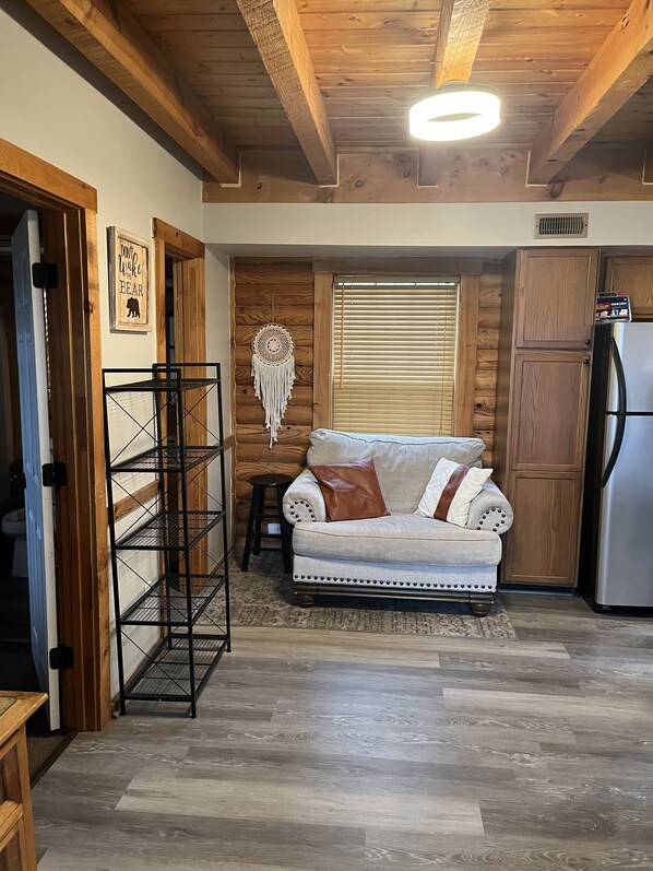 A cozy kitchen with a wooden ceiling, a white sofa, and a refrigerator.