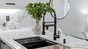Une cuisine moderne avec un plan de travail blanc, un évier et une plante.