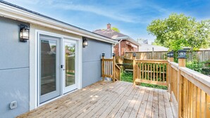 Une terrasse en bois avec une porte-fenêtre coulissante donnant sur un patio abrité.