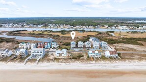 An aerial view of a coastal residential area with houses near the beach and a body of water.