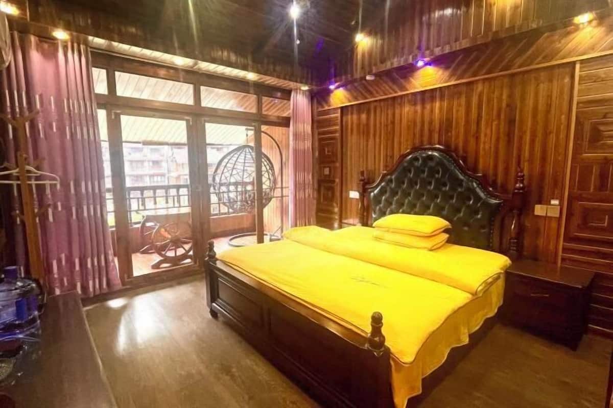 A wooden-paneled room with a bed, a chair, and a view through a glass door.
