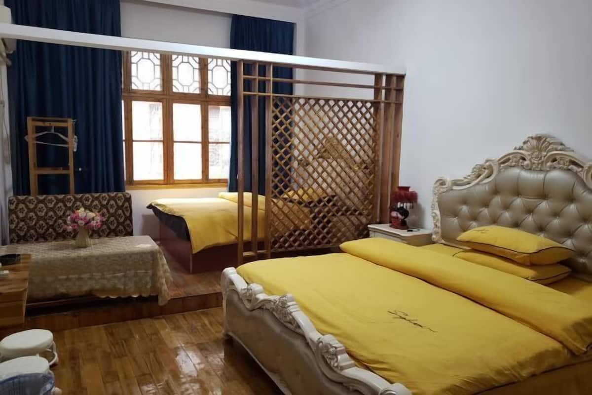 A room with a bed, two bedside tables, a window with curtains, and a wooden partition.