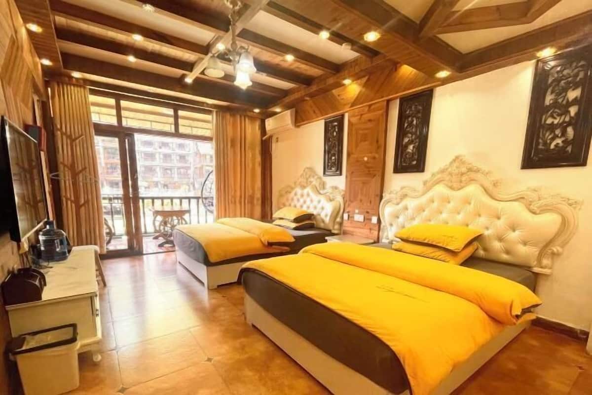 A hotel room with two beds, wooden ceiling beams, a television, and artwork on the walls.