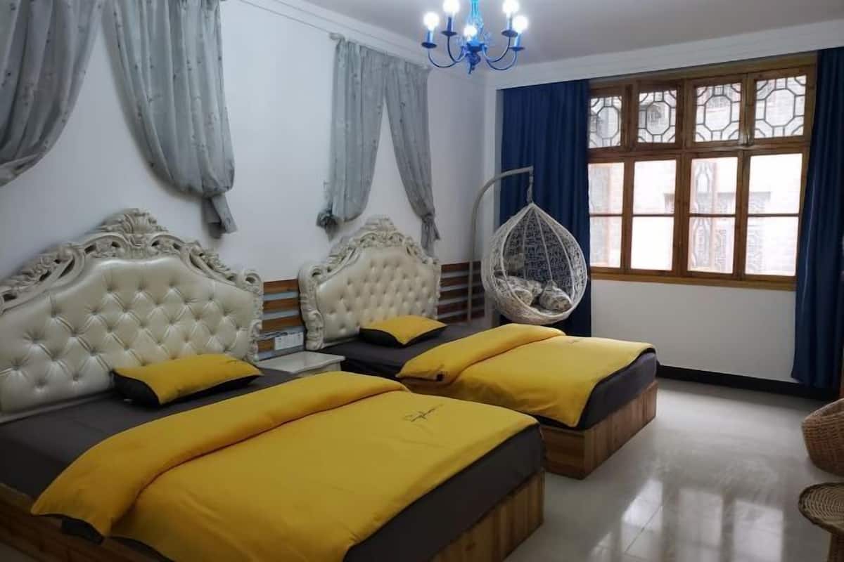 A hotel room with two beds, a hanging chair, and a large window with curtains.