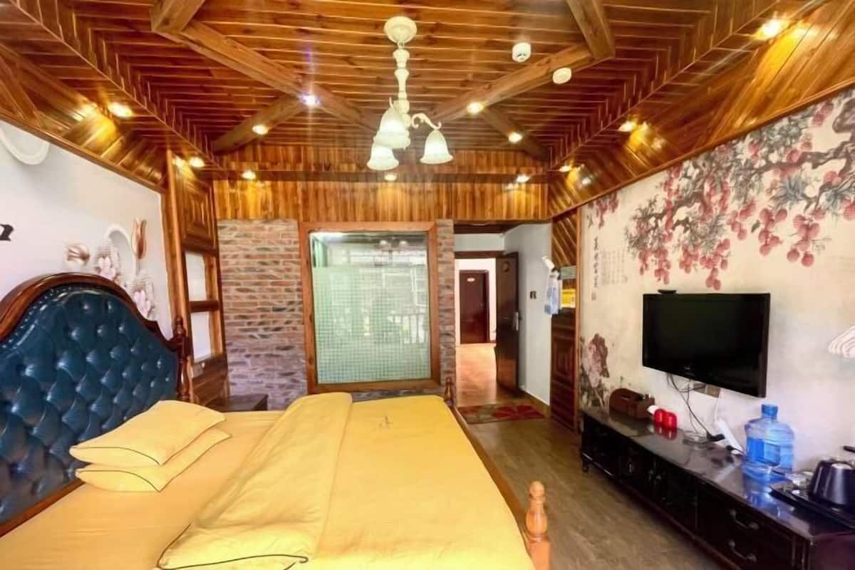 A room with a bed, a television, and a stone wall.