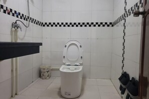 A small bathroom with a toilet, a sink, and a trash can. - Xiangyunge Inn (Fenghuang County)