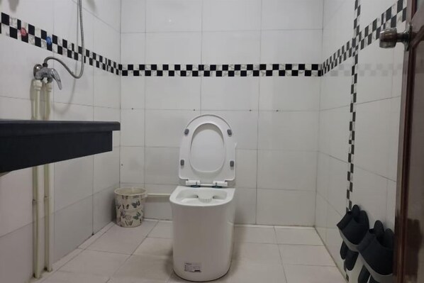 A small bathroom with a toilet, a sink, and a trash can. - Xiangyunge Inn (Fenghuang County)