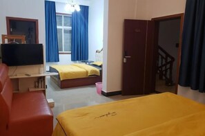 A hotel room with a bed, a desk with a television, a red couch, and a staircase. - Xiangyunge Inn (Fenghuang County)
