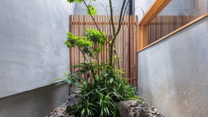 A small garden area with a variety of plants, rocks, and a wooden fence. - Kai  (Kyoto)