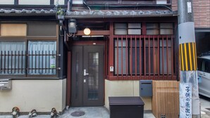 A traditional Japanese building with a dark wooden door, a tiled roof, and a small outdoor seating area. - Kai  (Kyoto)