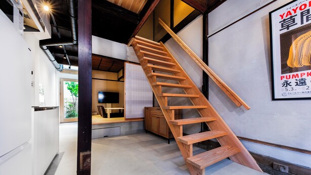 A modern interior with a wooden staircase, a kitchen area, and a poster on the wall. - Kai  (Kyoto)