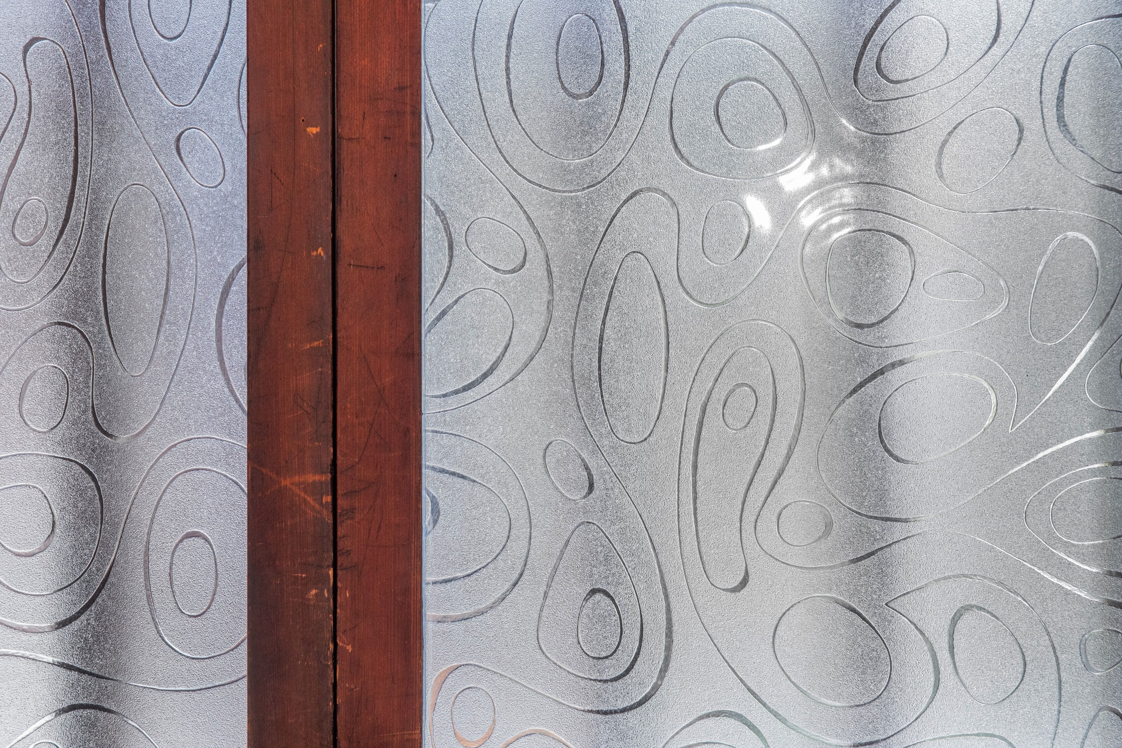 A close-up of a textured glass window with a wooden frame.