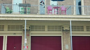 A fire station with two fire trucks, a no parking sign, and a balcony with chairs and umbrellas. - Charming 2bed, 2bath condo on The Strand, Galveston with WiFi, AC, garage (Galveston)
