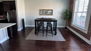 A dining area with a dark wooden table, two chairs, a decorative mirror, and a potted plant. - Charming 2bed, 2bath condo on The Strand, Galveston with WiFi, AC, garage (Galveston)