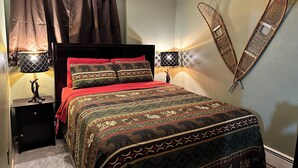 Une chambre à coucher comprenant un lit, deux tables de chevet avec des lampes, une chaise fixée au mur et un élément décoratif mural.