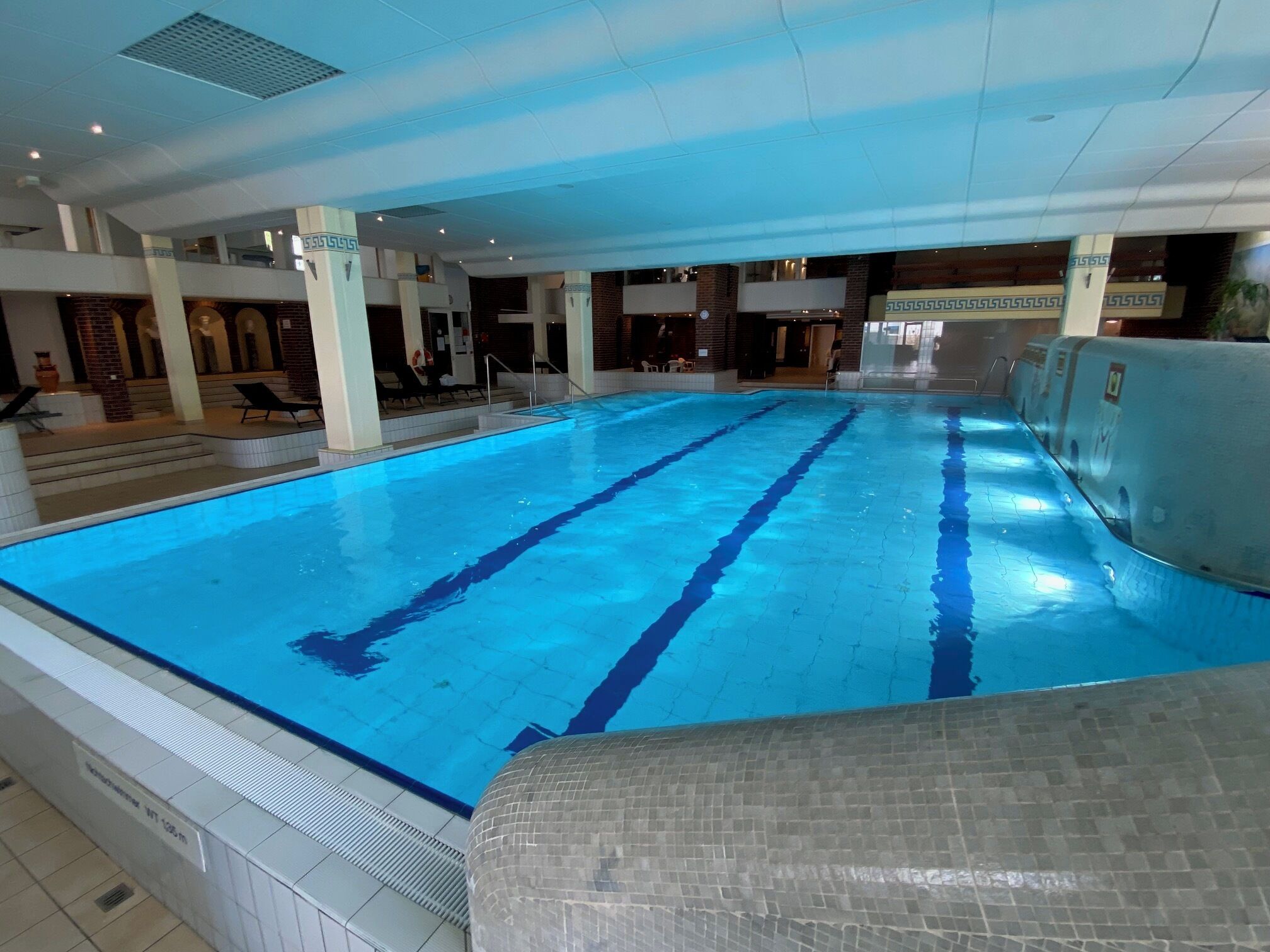 Una piscina interior amb marques de carrils ben definides, sòl i paret de rajola.