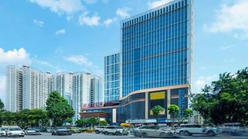 A modern high-rise building with a glass facade, surrounded by a busy street and other high-rise buildings.