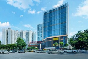 A modern high-rise building with a glass facade, surrounded by a busy street and other high-rise buildings. - Chuanyu Huisen Hotel (Baise)