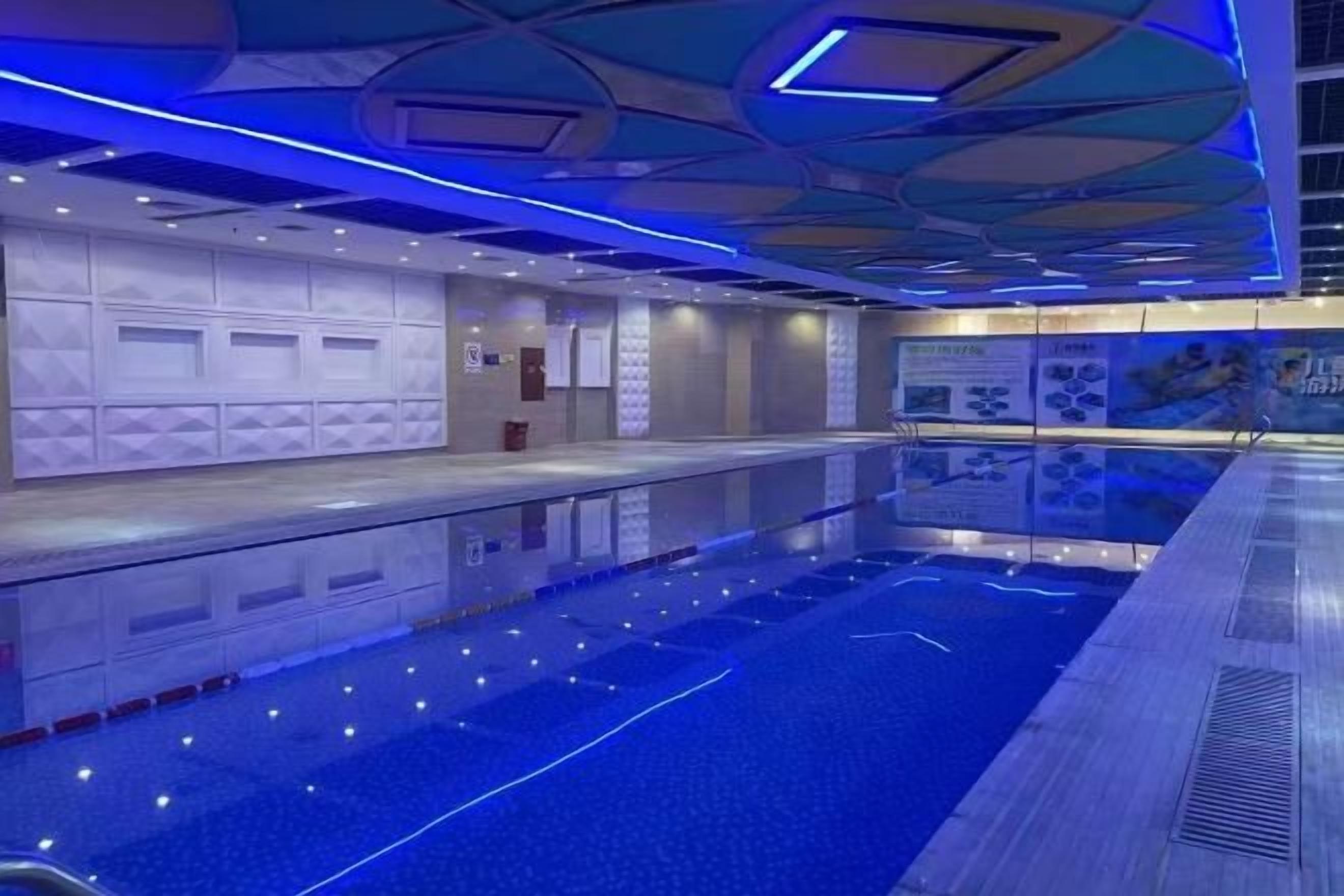 Una piscina interior moderna con forma larga y estrecha y superficie reflectante.